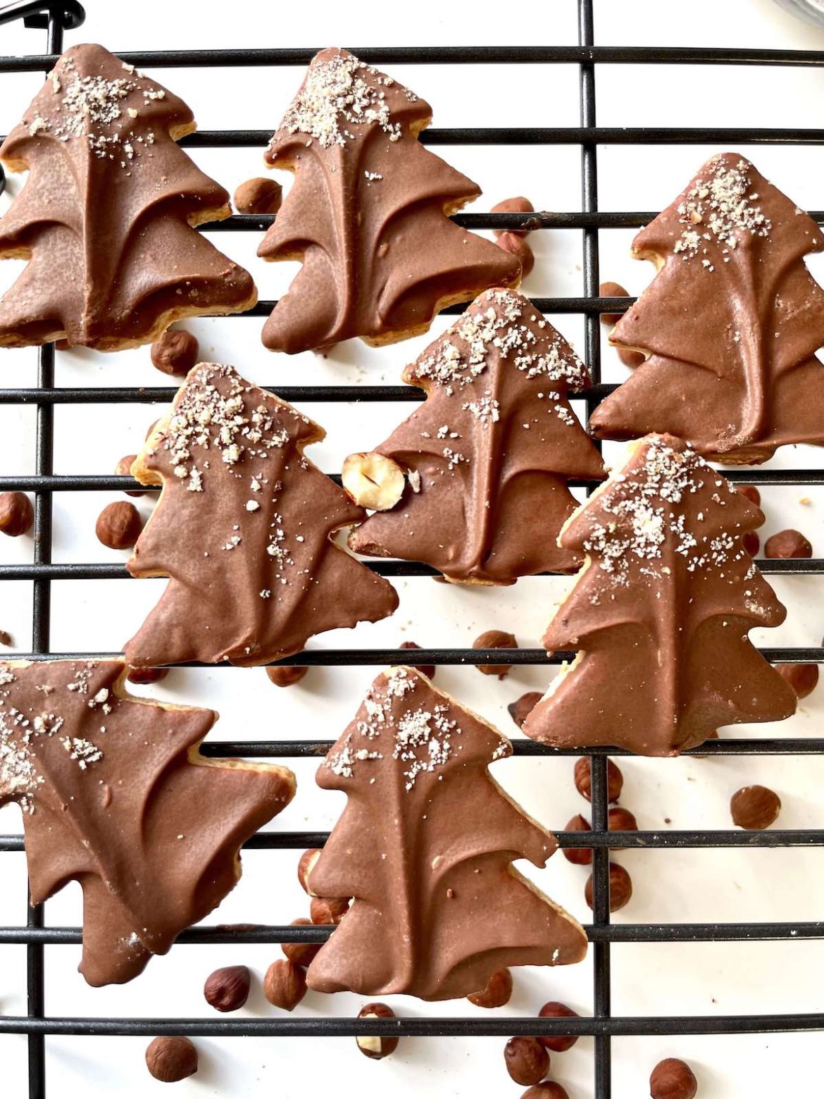 Sablés noisette chocolat en forme de sapin de noel sur une grille noire