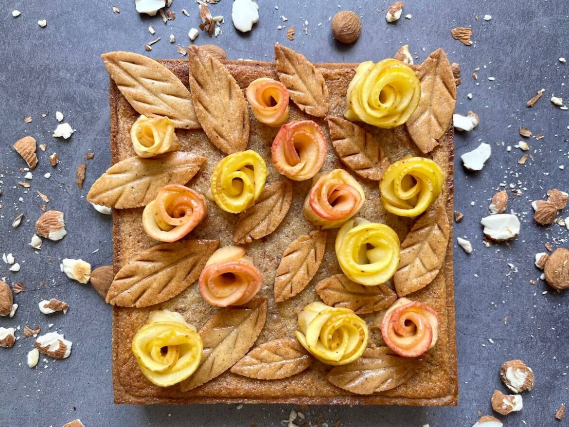 Tarte aux pommes et crème d'amande décorée de pommes en forme de roses et pétales en biscuit